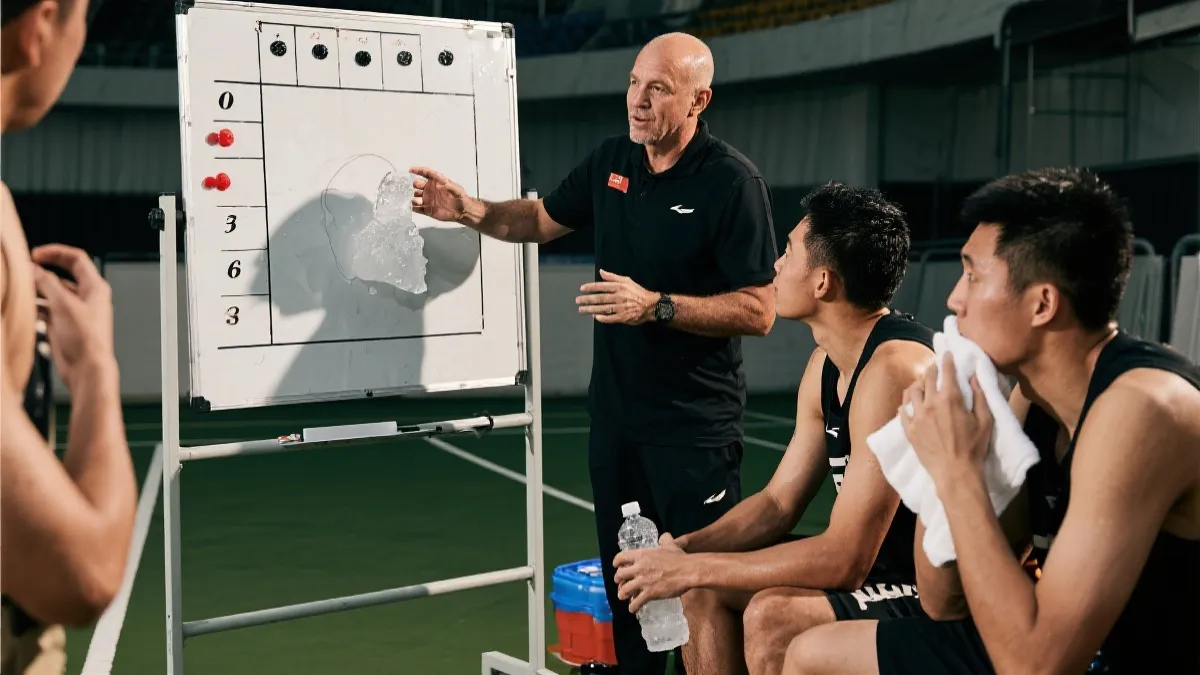 教练在补水暂停期间给球员讲解战术，球员用毛巾降温补水